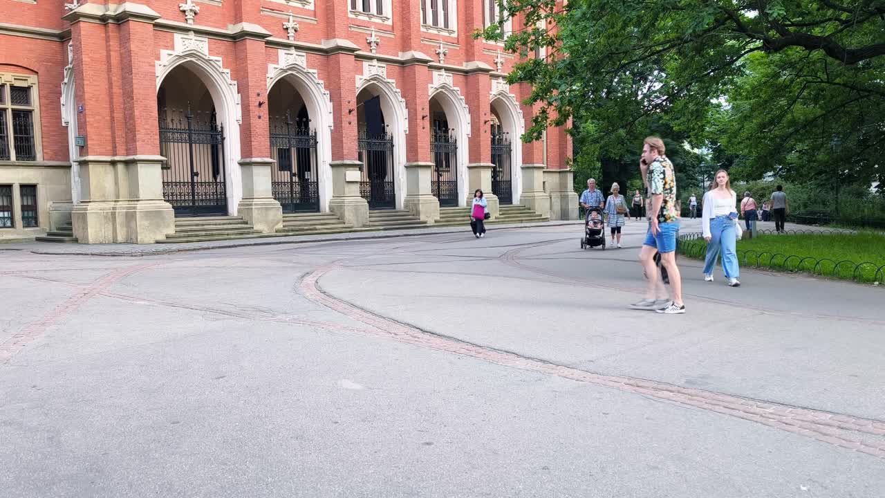 Tourists Stroll By the Jagiellonian University, a Historical University Located in Krakow, Poland - Slow Motion