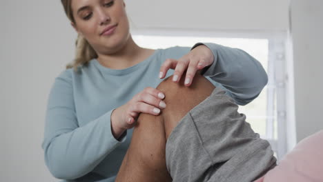 caucasian female physiotherapist checking knee of senior woman, copy space, slow motion