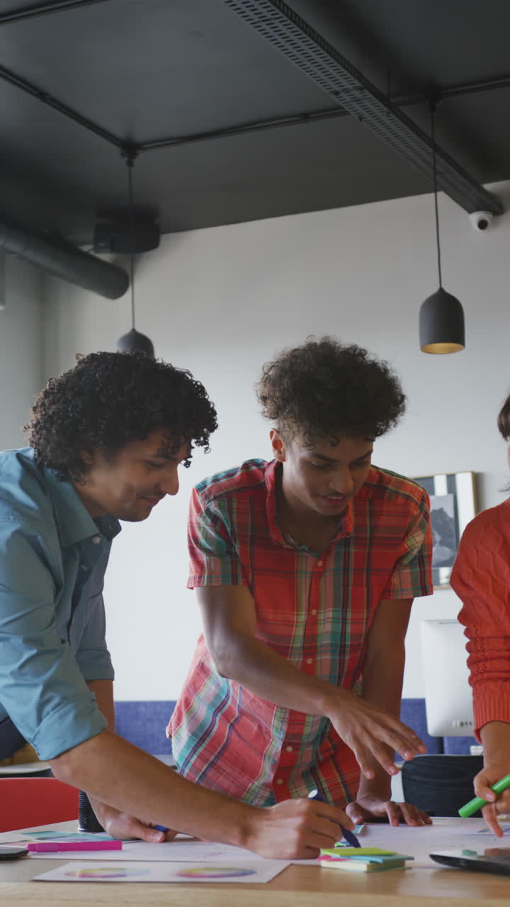 video vertical de personas de negocios felices y diversas discutiendo el trabajo durante una reunión en la oficina