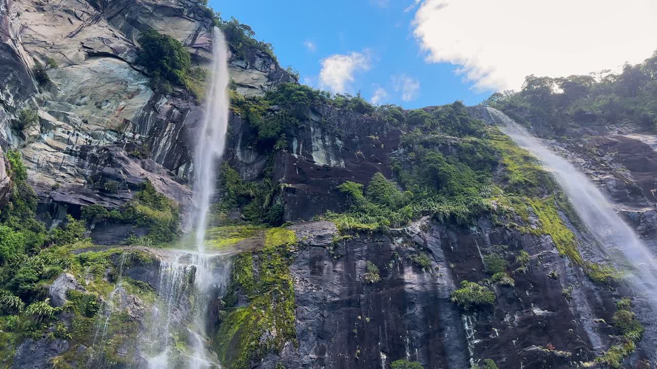 Olhando para as imponentes cachoeiras gêmeas em Milford Sound, Parque Nacional de Fiordland, Nova Zelândia. Penhascos envoltos em névoa, água corrente e paisagens dramáticas de fiordes criam uma cena de tirar o fôlego