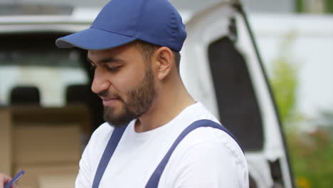 repartidor con gorra azul llenando un documento en la calle