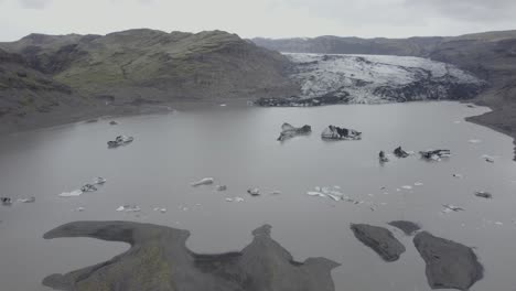 Vista-Aérea-Con-Vistas-A-Los-Bloques-De-Hielo-Y-Al-Glaciar-Solheimajokull---Inclinación,-Disparo-De-Drones