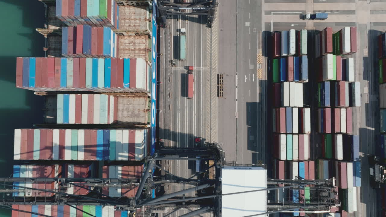 Truck driving in a lane under the gantry cranes while loading a giant container vessel in the port in Hong Kong
