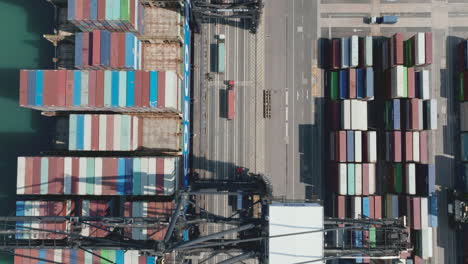 Truck-driving-in-a-lane-under-the-gantry-cranes-while-loading-a-giant-container-vessel-in-the-port-in-Hong-Kong