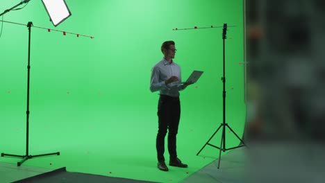 handsome young man wearing casual jeans and shirt, using laptop computer in green screen mock up chroma key studio. business, corporate office, work, technology concept.