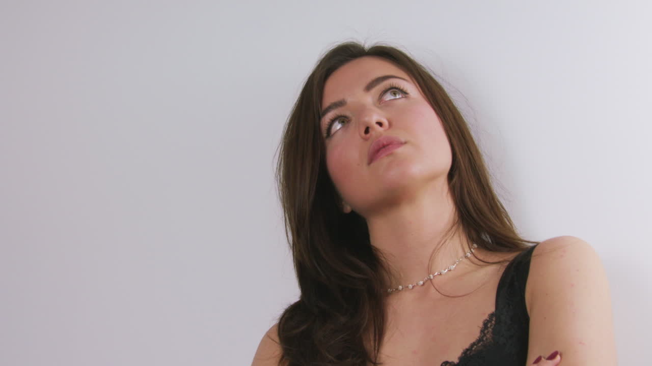 chica de aspecto nervioso apoyada contra una pared blanca con los brazos cruzados