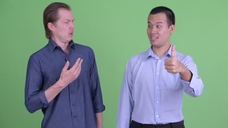 two businessman having different opinions against green studio background