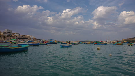 Time-lapse-De-Nubes-Moviéndose-Sobre-Barcos-Anclados-En-La-Soleada-Marsaxlokk,-Malta