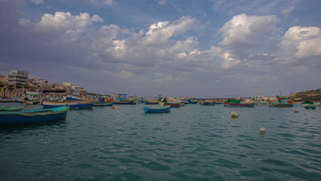 time-lapse of clouds moving over a anchored boats in sunny marsaxlokk, malta