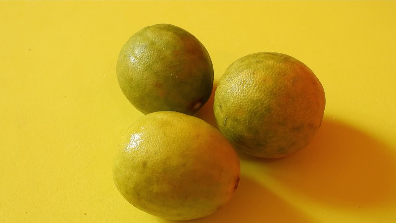 vista superior de tres limones girando sobre fondo amarillo