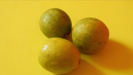 Top-view-of-three-lemons-rotating-on-yellow-background