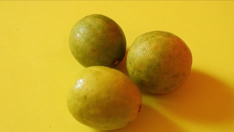 vista superior de tres limones girando sobre fondo amarillo