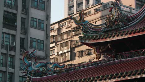 roof decorative sculptures at longshan temple with a modern building on the background