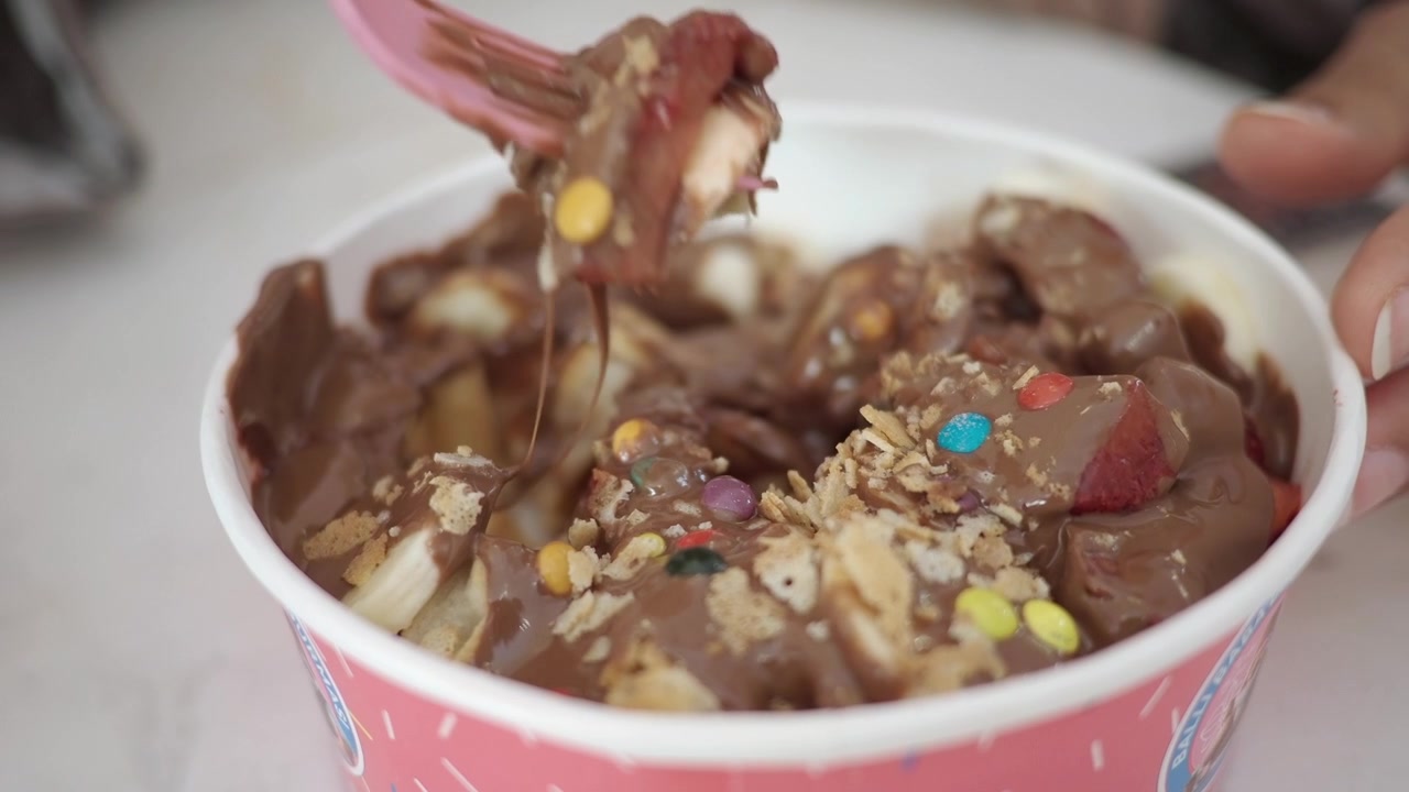 Persona che mangia frutta ricoperta di cioccolato e un dessert waffle