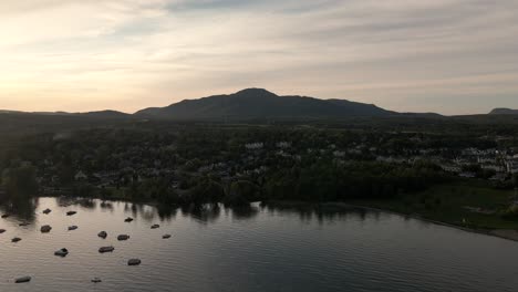 boats moored over the calm water of lake memphremagog in magog, quebec, canada on a sunset - aerial drone