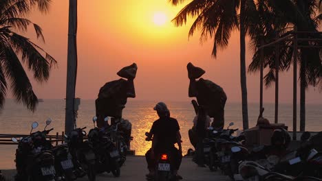 local residents enjoy a beautiful sunset on phu quoc island, driving scooters with their hands in the air, embracing the moment and life’s simple pleasures while surrounded by the ocean.