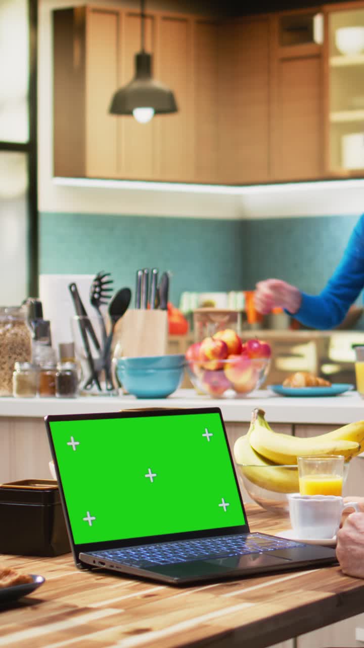 Vertical Video Green screen laptop with senior man sitting at the kitchen table
