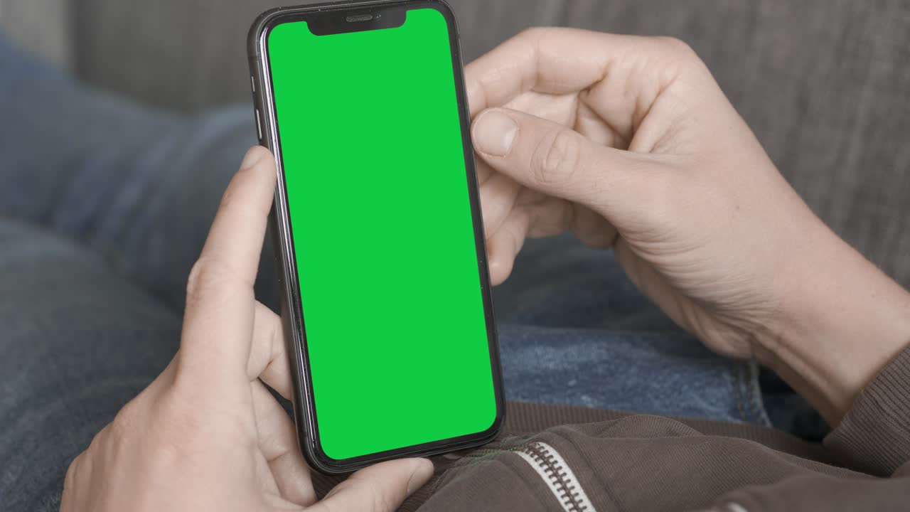 tocando y sosteniendo un iphone de pantalla verde
