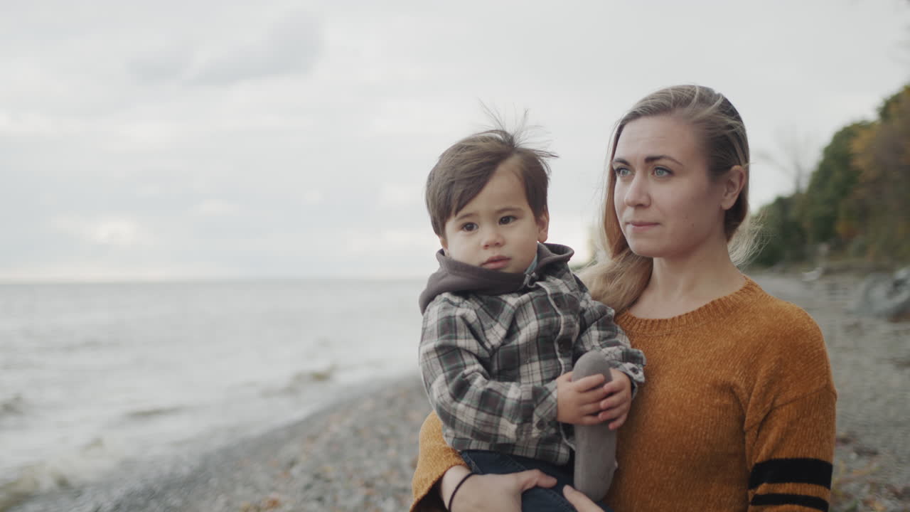 A young mother walks with her son on the shores of the picturesque Lake Ontario