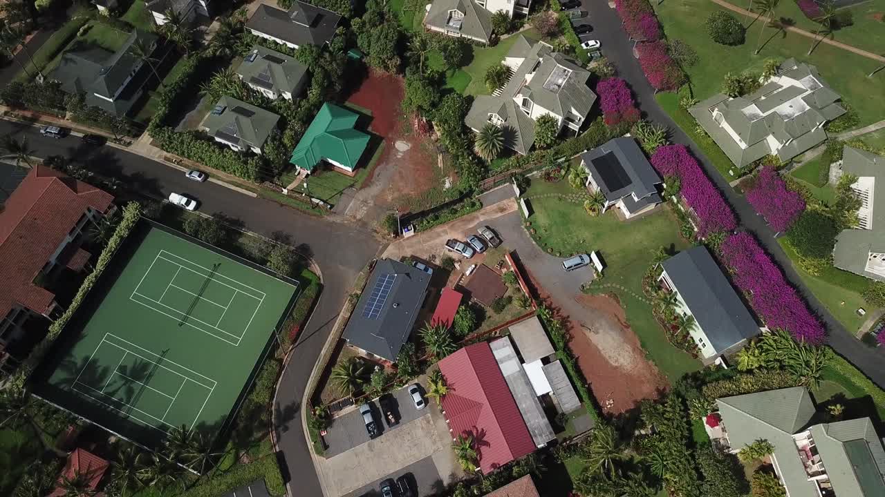Drone pan up from houses to reveal coast and town of Poipu in Kauai, Hawaii, United States on beautiful sunny day