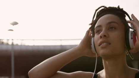 Vista-Frontal-De-Una-Joven-Afroamericana-Escuchando-Música-Con-Auriculares-En-La-Ciudad-4k