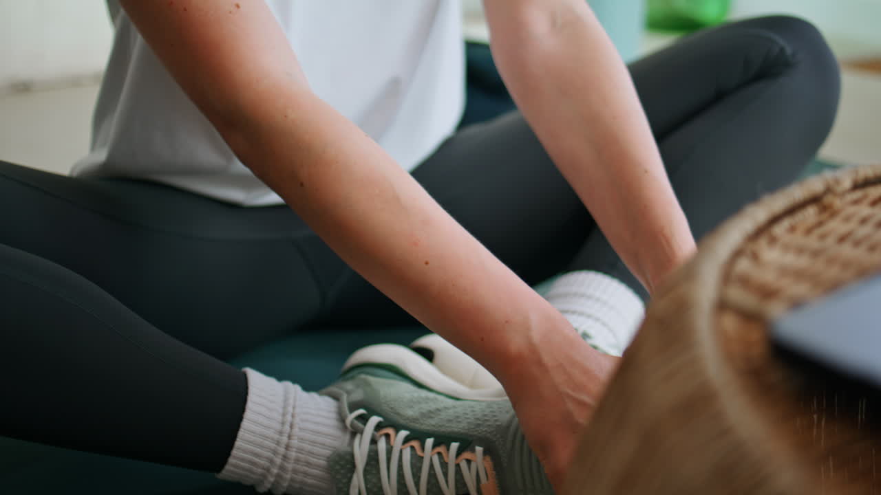 Sportswoman hands lying knees sitting yoga pose indoors closeup. Athletic woman