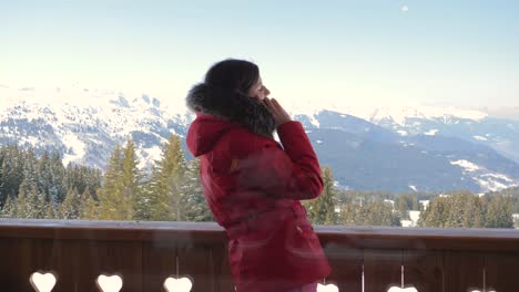 skier on the veranda in the chalet talking on the smartphone in the winter