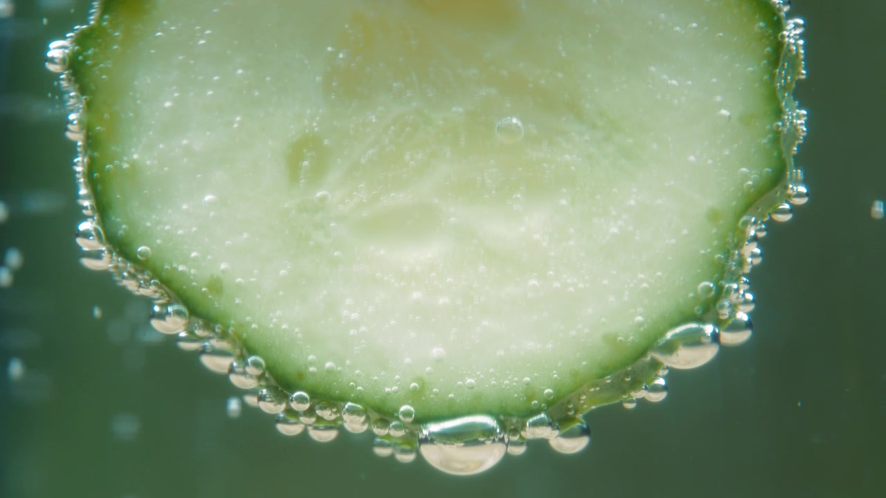 Macro primo piano di una fetta di cetriolo in acqua frizzante con bolle d'aria