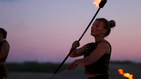 a group of professional circus performers with fire shows dance shows in slow motion using flame-throwers and rotating the torches burning objects.