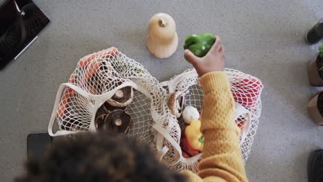 overhead view of african american woman unpacking groceries in kitchen, in slow motion