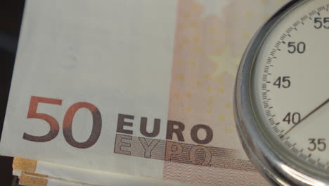 stopwatch with euro banknotes on background