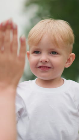 un primer plano de un tierno momento cuando un niño recibe un high five de una mujer con uñas hermosamente pintadas