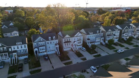 row of townhouses with symmetrical facades and individual driveways at sunset