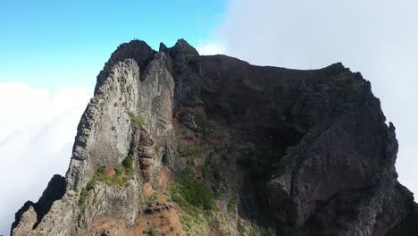 Drone shot moving up and forward over the edge of Pico das Torres in Madeira next to a group of three friends.