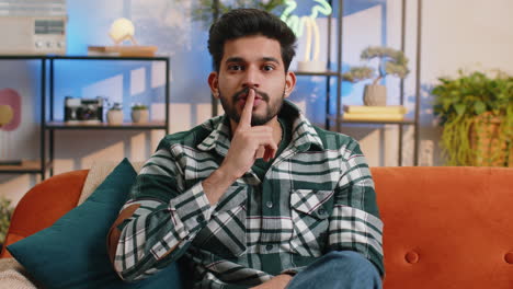 Indian-man-presses-finger-to-lips-makes-silence-hush-sign-do-not-tells-gossip-secret,-quiet-at-home