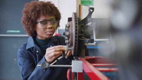 female students checking car brake discs on auto mechanic course at college