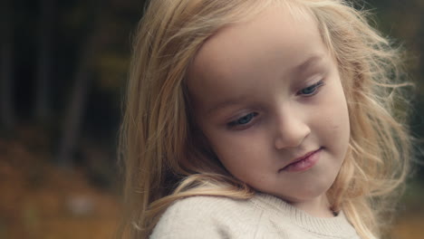 close up young girl's face as wind blows blonde hair, portrait