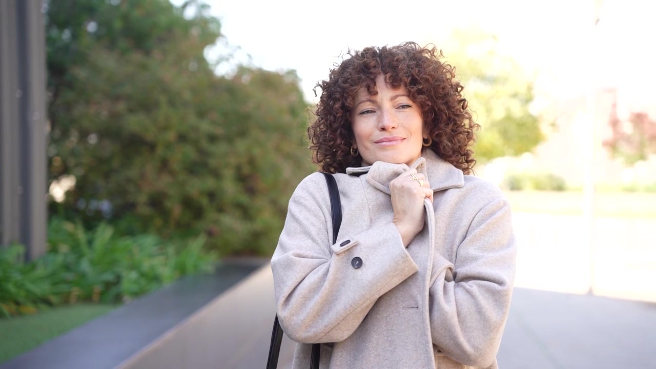 Una mujer alegre usando felizmente su smartphone al aire libre bajo una luz natural brillante.