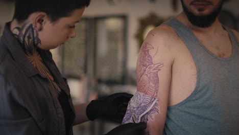 mujer caucásica preparándose para hacer un tatuaje para su cliente.