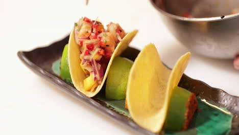 chef filling taco shells with chopped vegetables and fish