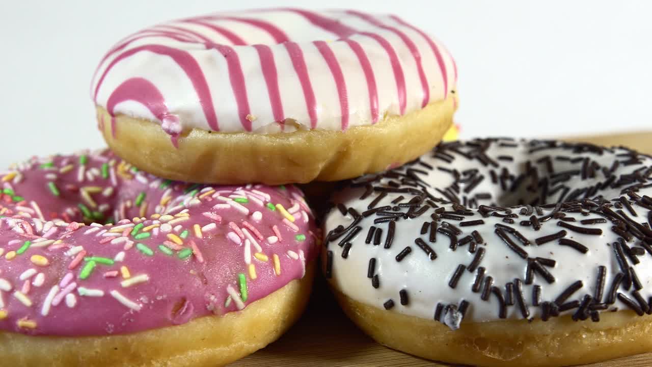 rosquillas giratorias con diferentes rellenos en la mesa. deliciosa rosquilla dulce girando en un plato. rosquilla brillante y colorida macro disparo de primer plano girando sobre un fondo blanco. bucle sin costuras.