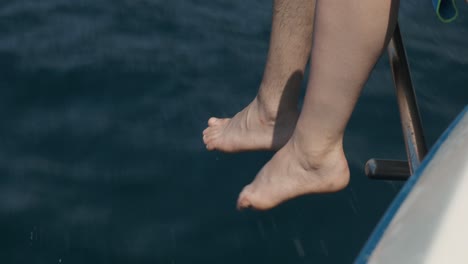 Paar-Füße,-Die-über-Den-Rand-Eines-Schnellboots-Hängen,-Handgehalten