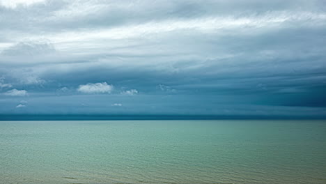 Timelapse-footage-of-a-beach-with-clear-blue-water-and-moving-clouds-above-it