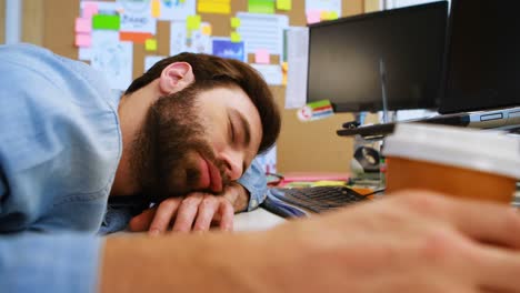 Male-graphic-designer-sleeping-at-desk