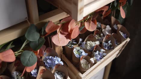 Rustic wooden box holding flower petal cones with natural foliage accents