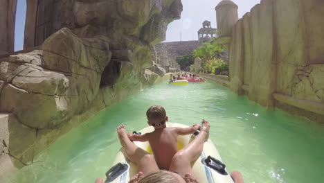 child with mother getting excited with lazy river ride in water park