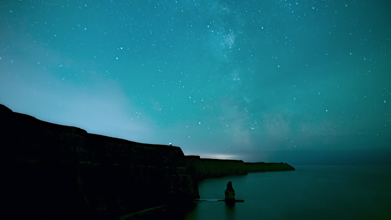 Timelapse do núcleo da Via Láctea nascendo sobre os Cliffs of Moher em uma noite clara com estrelas acima do Oceano Atlântico