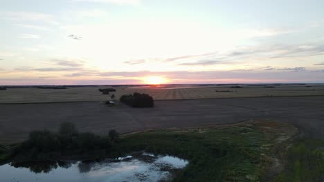 late summer sunset over expansive farmland and a tiny lake in rural southern alberta, canada