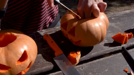 mujer vaciando el interior de una calabaza con la cara tallada y preparada para halloween