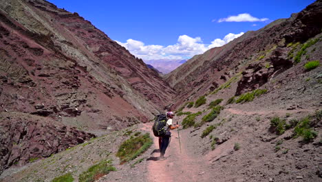 Handheld-tracking-shot-of-hikers-walking-on-a-dusty-road-on-a-mountain-side,-daytime